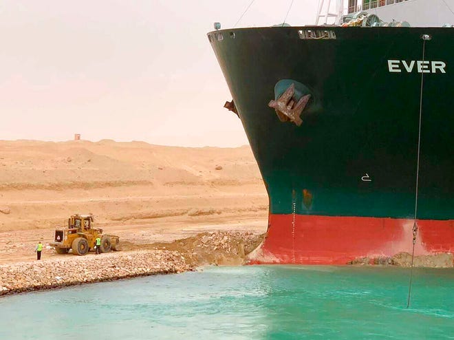 In this photo released by the Suez Canal Authority, a cargo ship, named the Ever Green, sits with its bow stuck into the wall Wednesday, March 24, 2021, after it turned sideways in Egyptâ€™s Suez Canal, blocking traffic in a crucial East-West waterway for global shipping. An Egyptian official warned Wednesday it could take at least two days to clear the ship. (Suez Canal Authority via AP)