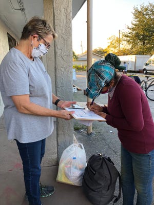 Ruth DeYoe of Misión Peniel in Immokalee requests the signature of a farmworker who is receiving financial help from the social services organization in January 2021 after the woman's son tested positive for the coronavirus and she was unable to work.
