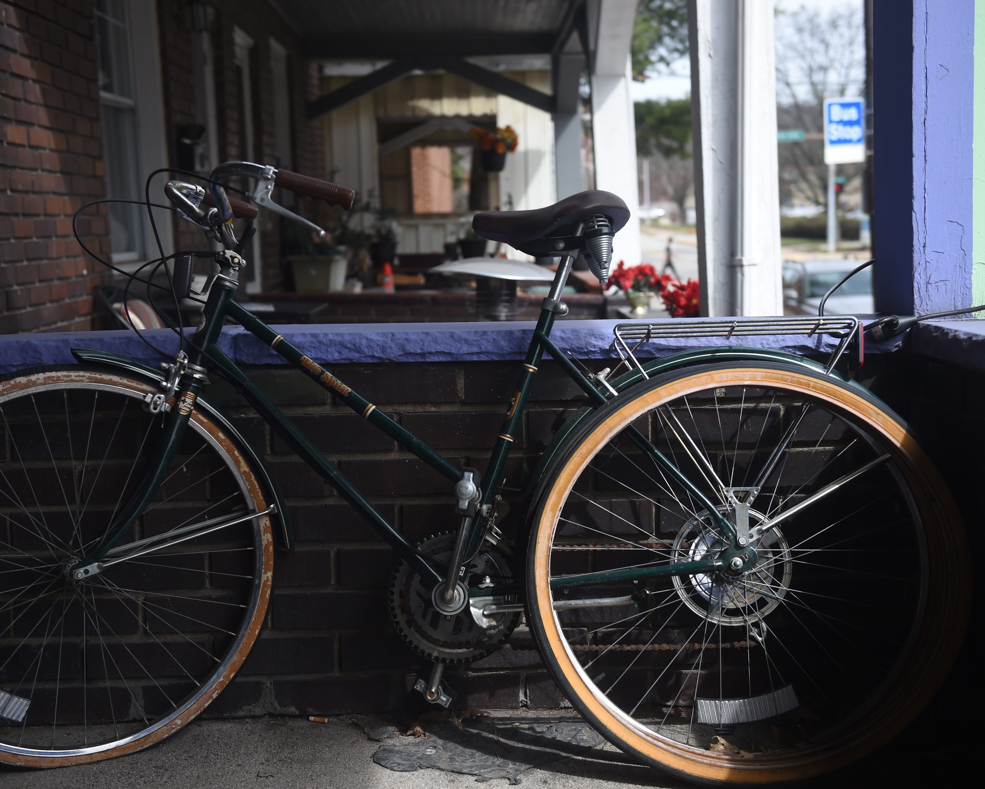 A bicycle sits outside Sharyn Sefton's apartment in Pittsburgh's Edgewood neighborhood. The 22-year-old Sefton purchased the bike to make traveling to work easier. The bike blew a tire and has remained shelved on the porch until Sefton can save enough to afford a new tire.