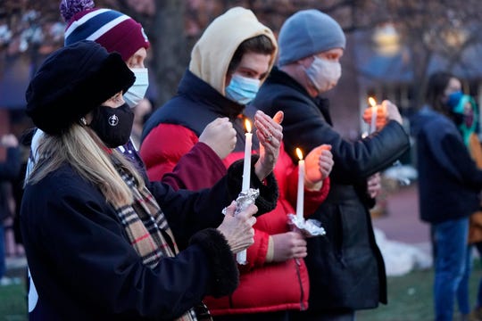 Mourners shield the flames of their candles from the wind at a vigil for the victims of a mass shooting at a grocery store earlier in the week, Wednesday, March 24, 2021, outside the courthouse in Boulder, Colo. 