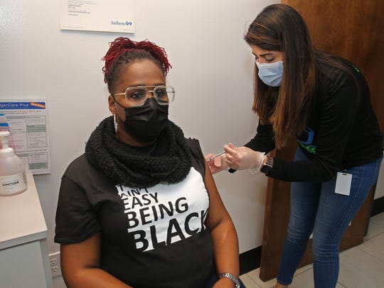 Sylvia Holmes, 46, left, receives a COVID-19 vaccination from pharmacist Dimmy Sokhial of Hayat Pharmacy on Saturday, March 27, 2021, at Gee’s Clippers, 2200 N. King Drive in Milwaukee. "It's a sense of relief," Holmes said.