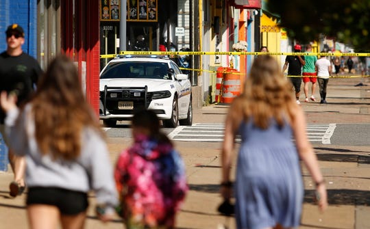 Tourists navigate police tape blocking several streets along the Virginia Beach Oceanfront on Saturday, March 27, 2021, the morning after a fatal shooting in Virginia Beach, Va.