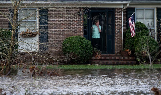 A woman surveys flood damage outside her home in Brentwood, Tenn., Sunday, March 28, 2021.