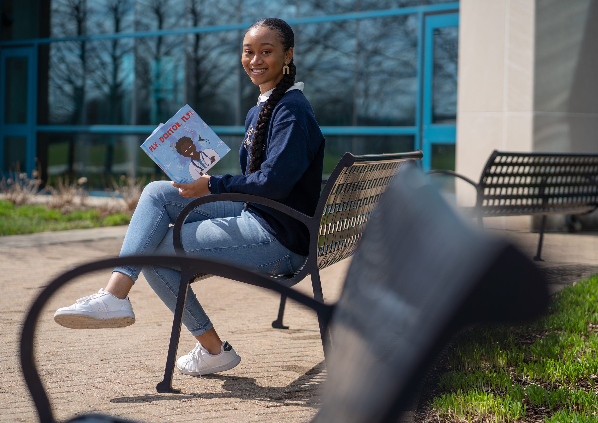 Lyndsay Archer, 23, of Southfield shows the children's book she recently wrote titled, "Fly, Doctor, Fly!" outside of the Southfield Public Library in Southfield on Friday, March 26, 2021. Archer co-illustrated the book with the inspiration behind it, her dad, Phillip. The book highlights Black and brown doctors. Archer is the founder of nonprofit, Roots Strong, which works toward serving youth locally and globally, centered around education, literacy and health.  
Her nonprofit has built two libraries in Jamaica.