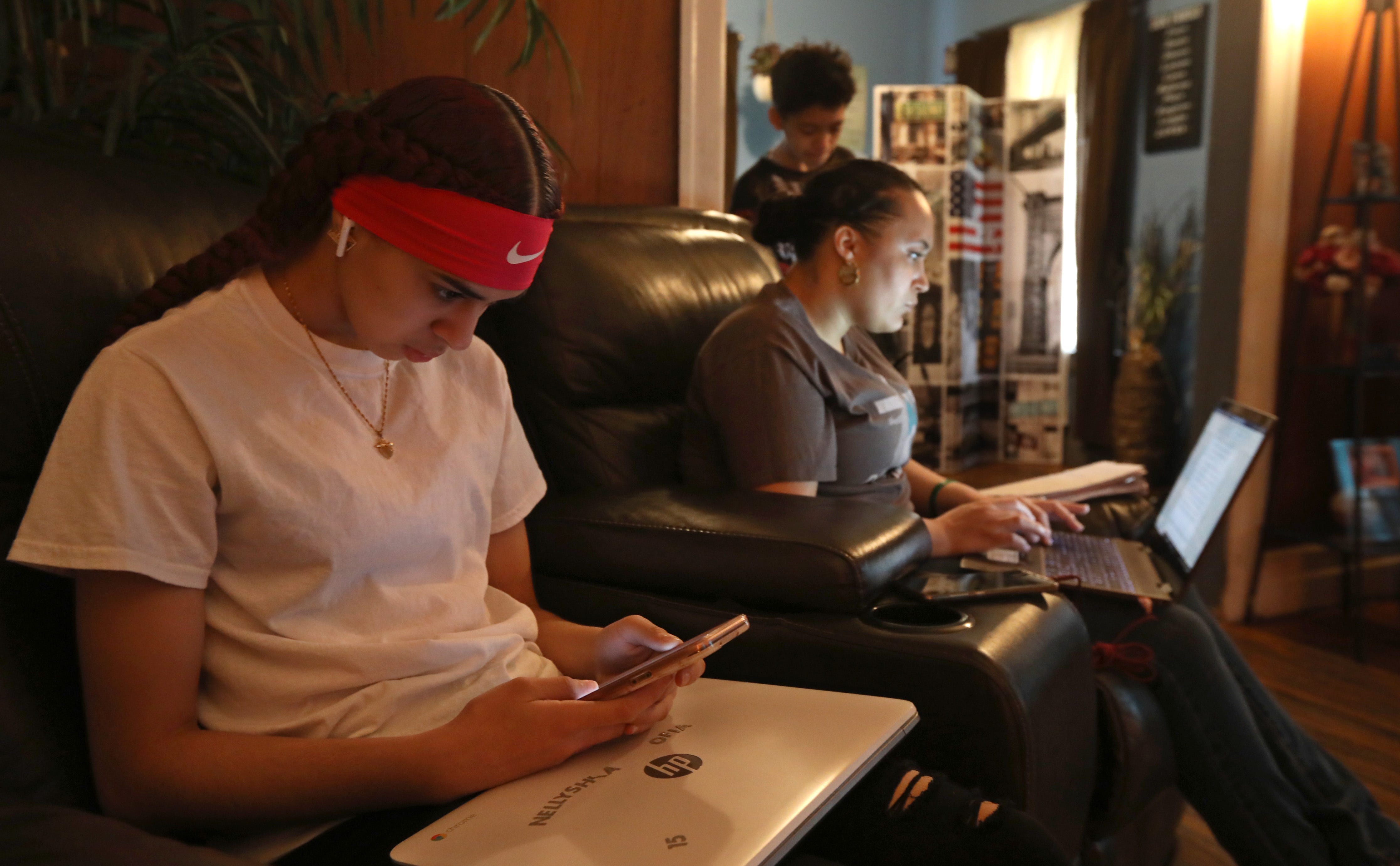 East High senior Reina Sepulveda, with all her work done for the day, catches up with friends on her iPhone as her mother, Zumarie Sepulveda, works on her assignments for her classes at SUNY Brockport as the entire family continues their remote learning at their home in Rochester Wednesday, March 24, 2021.