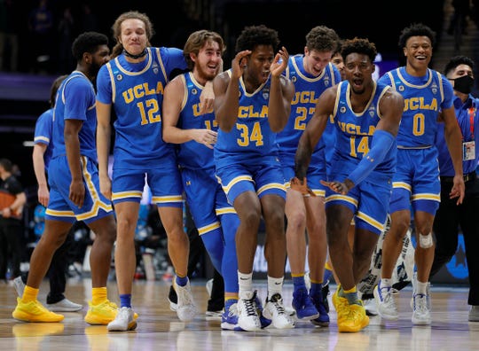 David Singleton of the UCLA Bruins and Kenneth Nwuba celebrate with teammates after defeating the Alabama Crimson Tide 88-78 in overtime in the Sweet Sixteen round game of the 2021 NCAA Men's Basketball Tournament at Hinkle Fieldhouse.