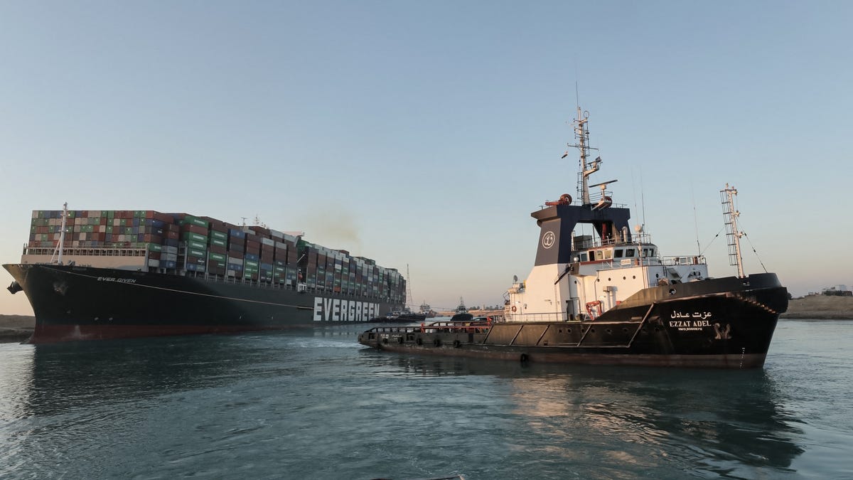 A handout picture released by the Suez Canal Authority on March 29, 2021 shows tugboats pulling the Panama-flagged MV Ever Given container ship, a 1,300-foot-long vessel, lodged sideways impeding traffic across Egypt's Suez Canal waterway.