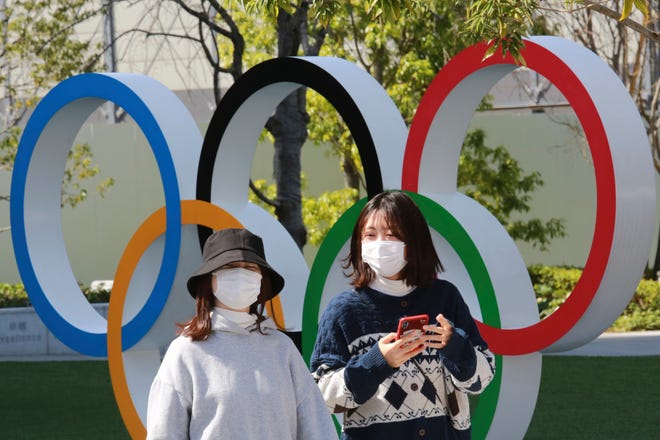 FILE - In this March 17, 2021, file photo, people walk past the Olympic rings in Tokyo. The Tokyo Olympics open in under four months, and the torch relay has begun to crisscross Japan with 10,000 runners. Organizers say they are mitigating the risks, but many medial expert aren't convinced.(AP Photo/Koji Sasahara)