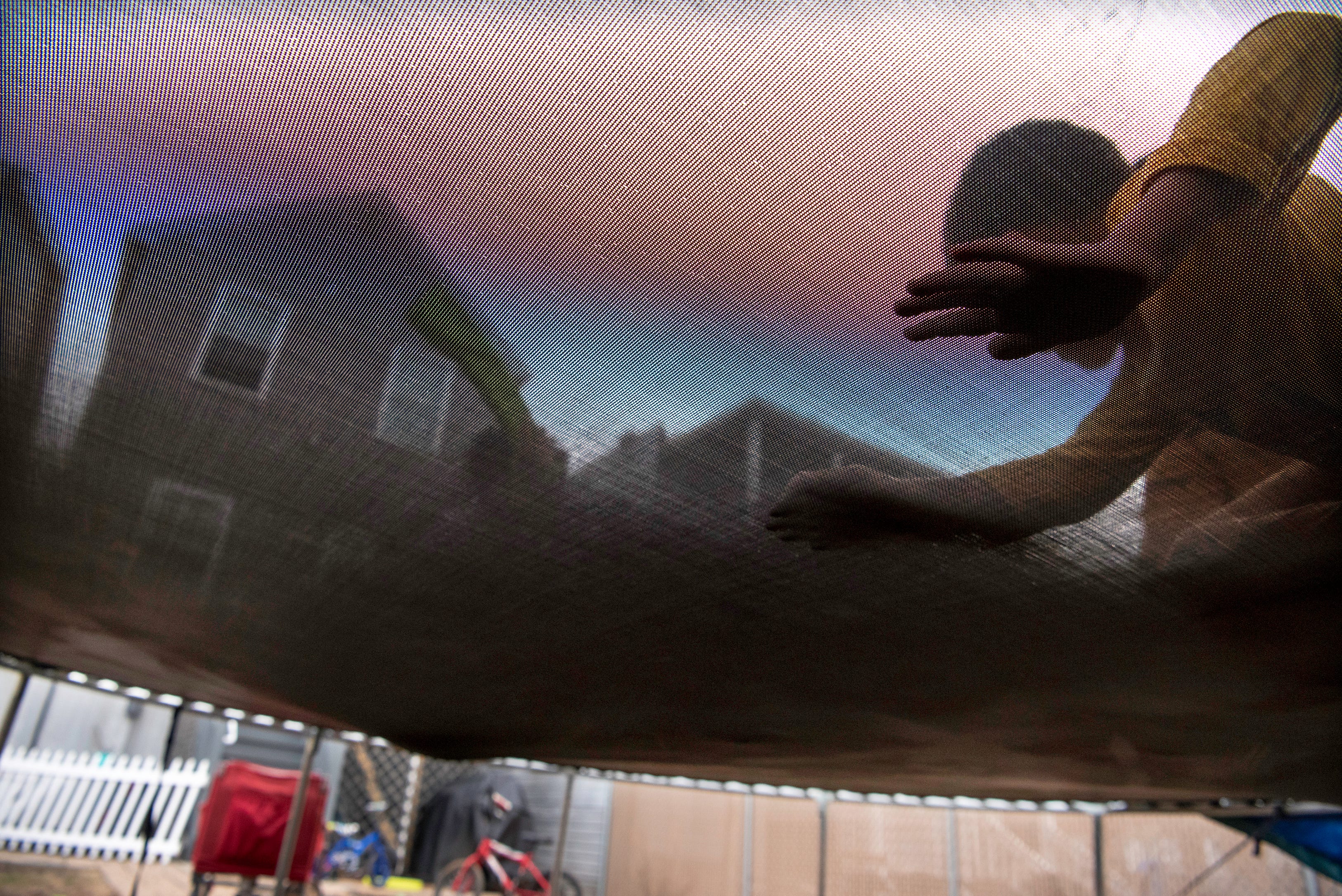 The De La Cruz brothers — Israel, 8, Benjamin, 5, and Raylin, 10 —play on a trampoline in the yard of their Hamilton Avenue home.