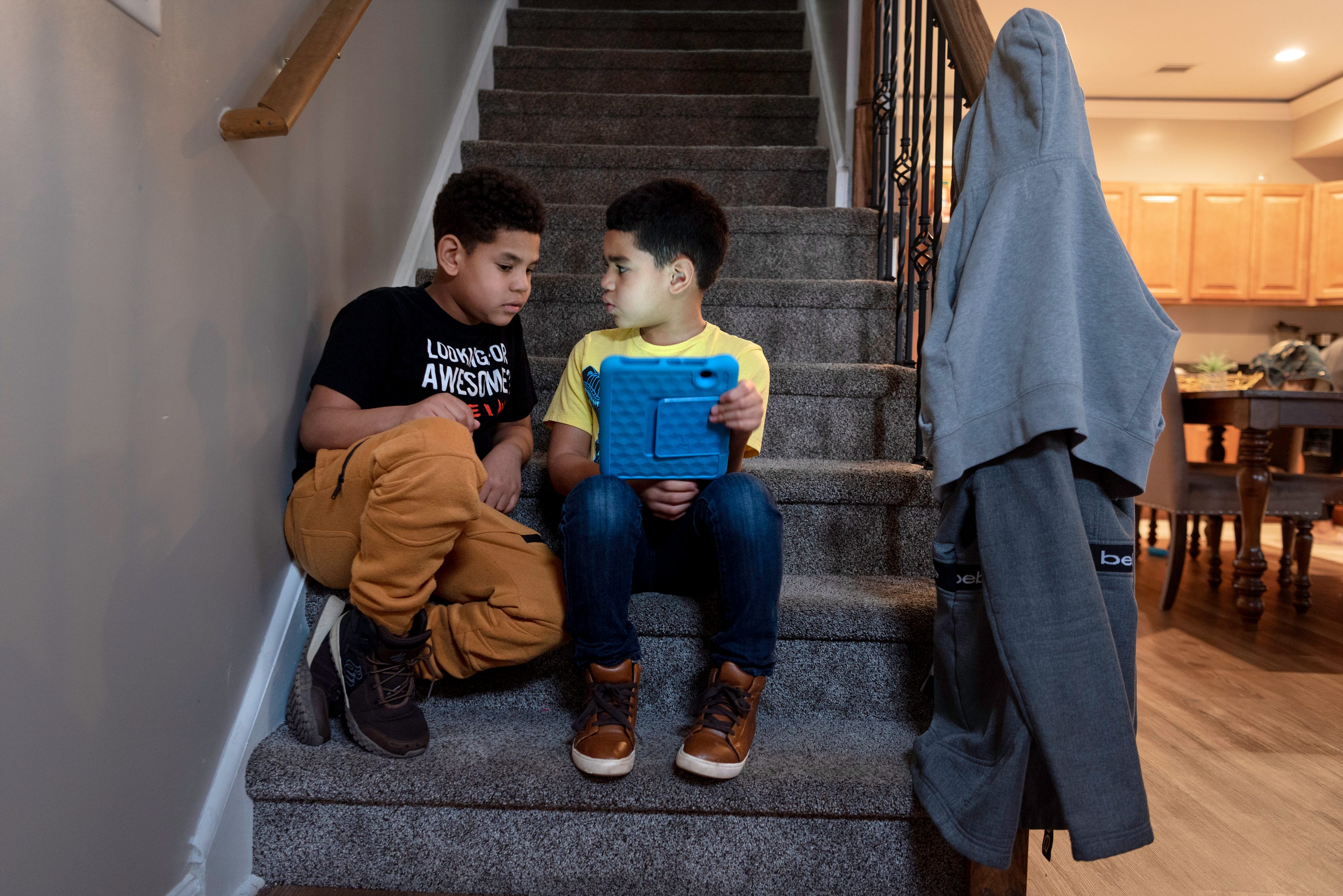 Brothers Israel De La Cruz 8,  and Emmanuel De La Cruz 6, find a quiet spot on the stairs to watch Israel's game on March 25, 2021. Dafani Peralta and Ramon De La Cruz and their six children, moved into their new home on 185 Hamilton Ave. in Paterson last year. The home is part of the "Hamilton 7," a group of seven Habitat for Humanity homes built on the block.