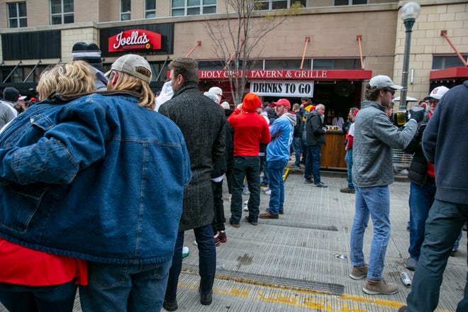 People wait in line for drinks to go at the Holy Grail Tavern and Grille at The Banks on Opening Day Thursday, April 1, 2021. The popular bar and restaurant would be part of a planned sale including the the Current and Radius luxury apartment buildings at The Banks riverfront development.