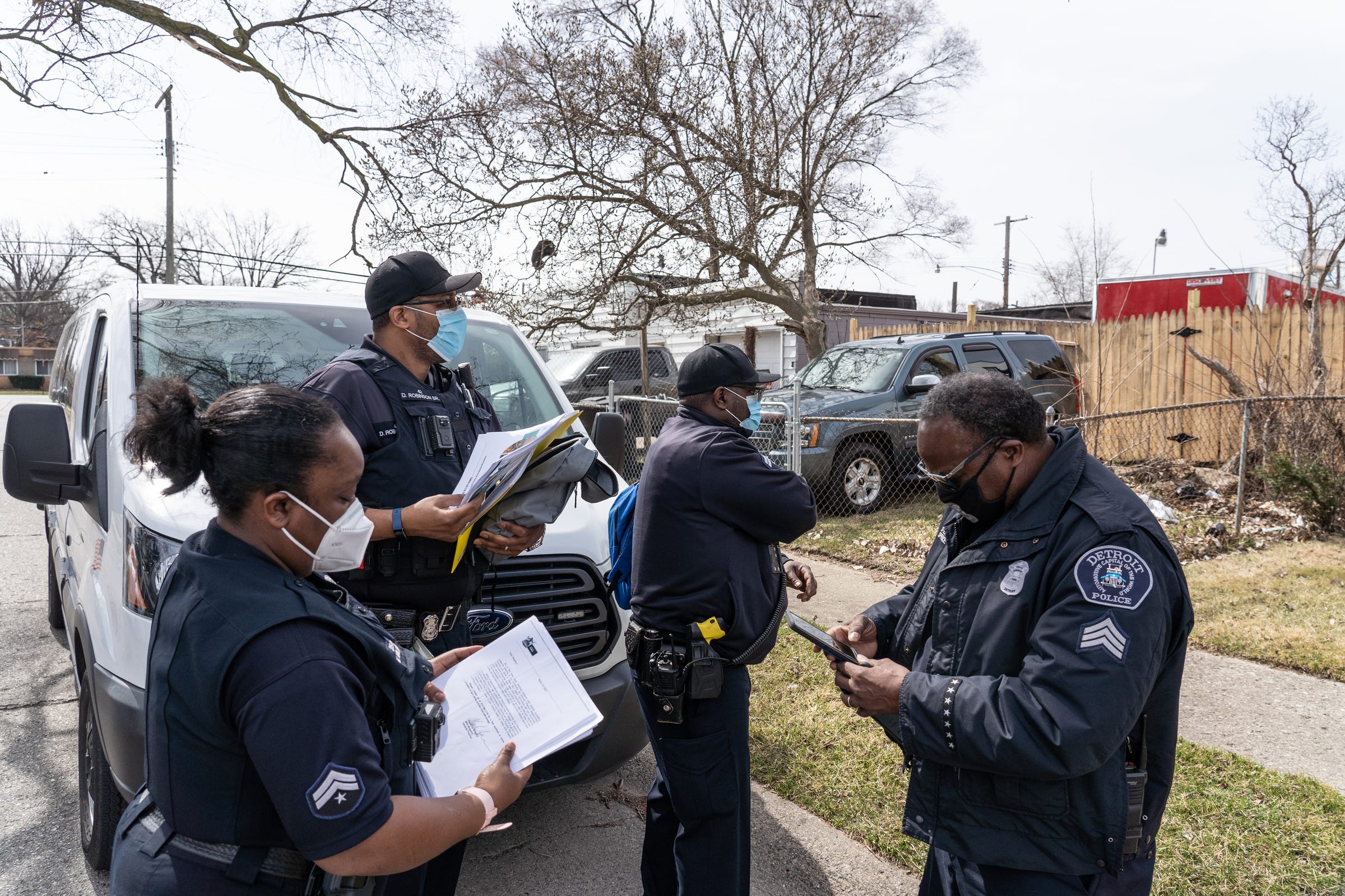 (Clockwise left to right) Detroit Police Department Neighborhood Police Officers Marcia Williams, Dan Robinson  and Eric Hill gather with Sergeant Charles Spruce before handing out gun safety information and gun locks while going door-to-door along Fenelon Street on Detroit's east side on Thursday, March 25, 2021.