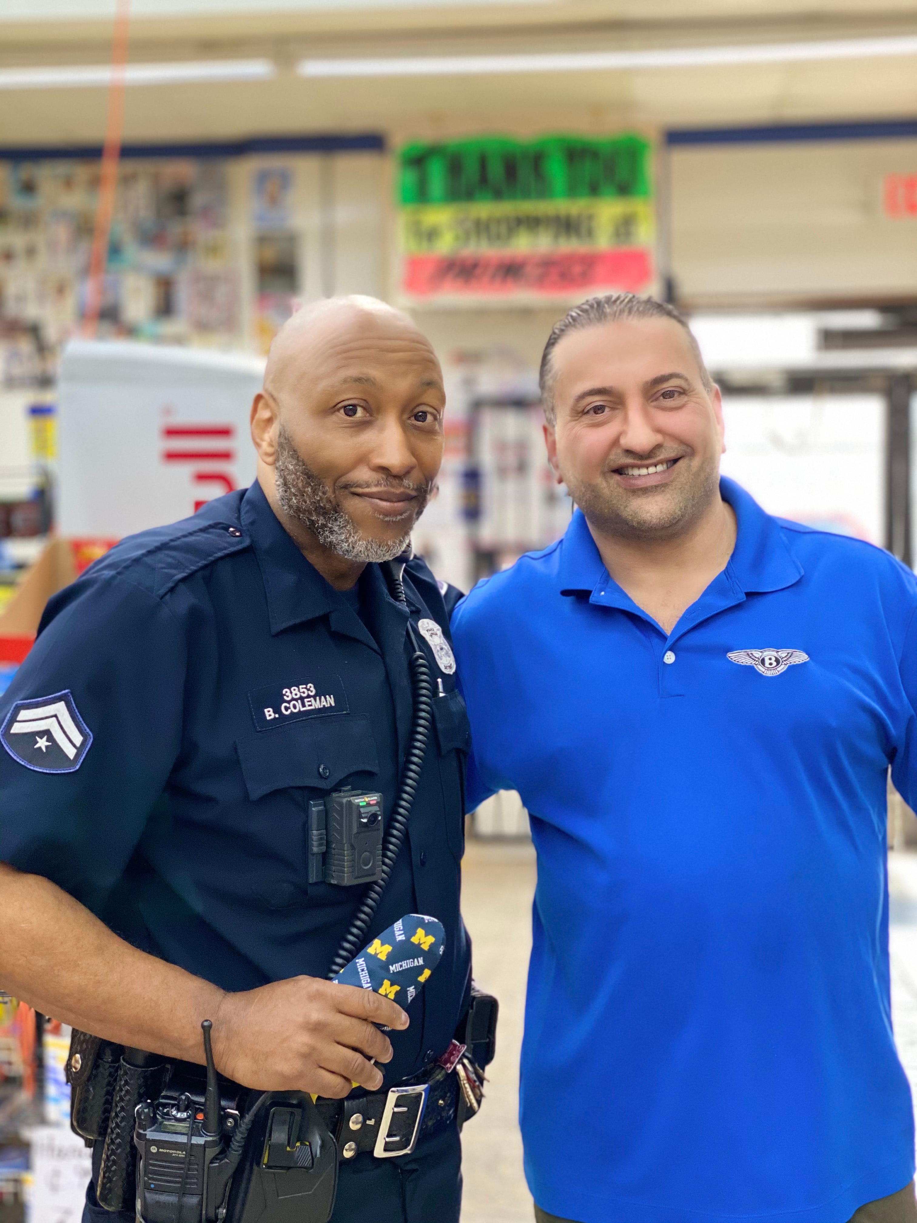 Officer Barren Coleman standing with Sal Sybri, 43, the owner of Princess Superette Market, a liquor store apart of the neighborhood Coleman patrols.