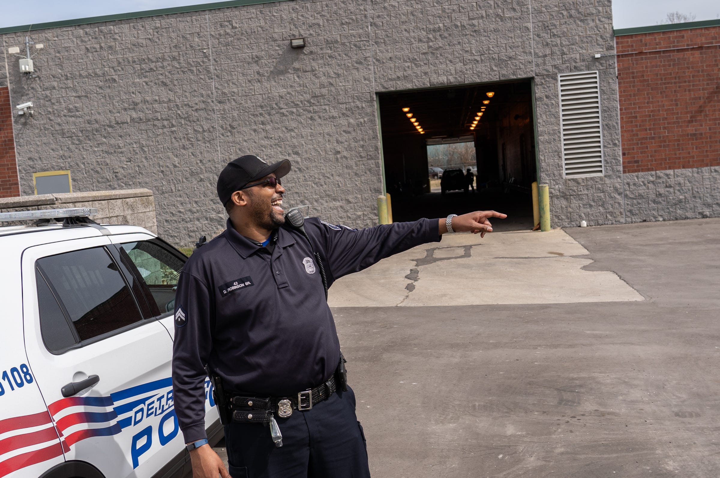 Detroit Police Department Neighborhood Police Officer Dan Robinson laughs with another officer after handing out gun safety information and gun locks door-to-door along Fenelon Street on Detroit's east side on Thursday, March 25, 2021.