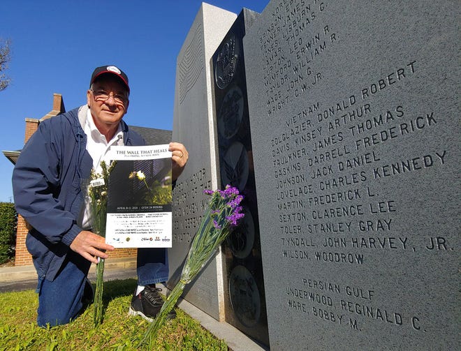 Vietnam veteran Ralph Aviles placed flowers and a poster about the 'Wall that Heals' visit to New Bern at a monument honoring Craven County war dead at the courthouse in New Bern on April 3.
