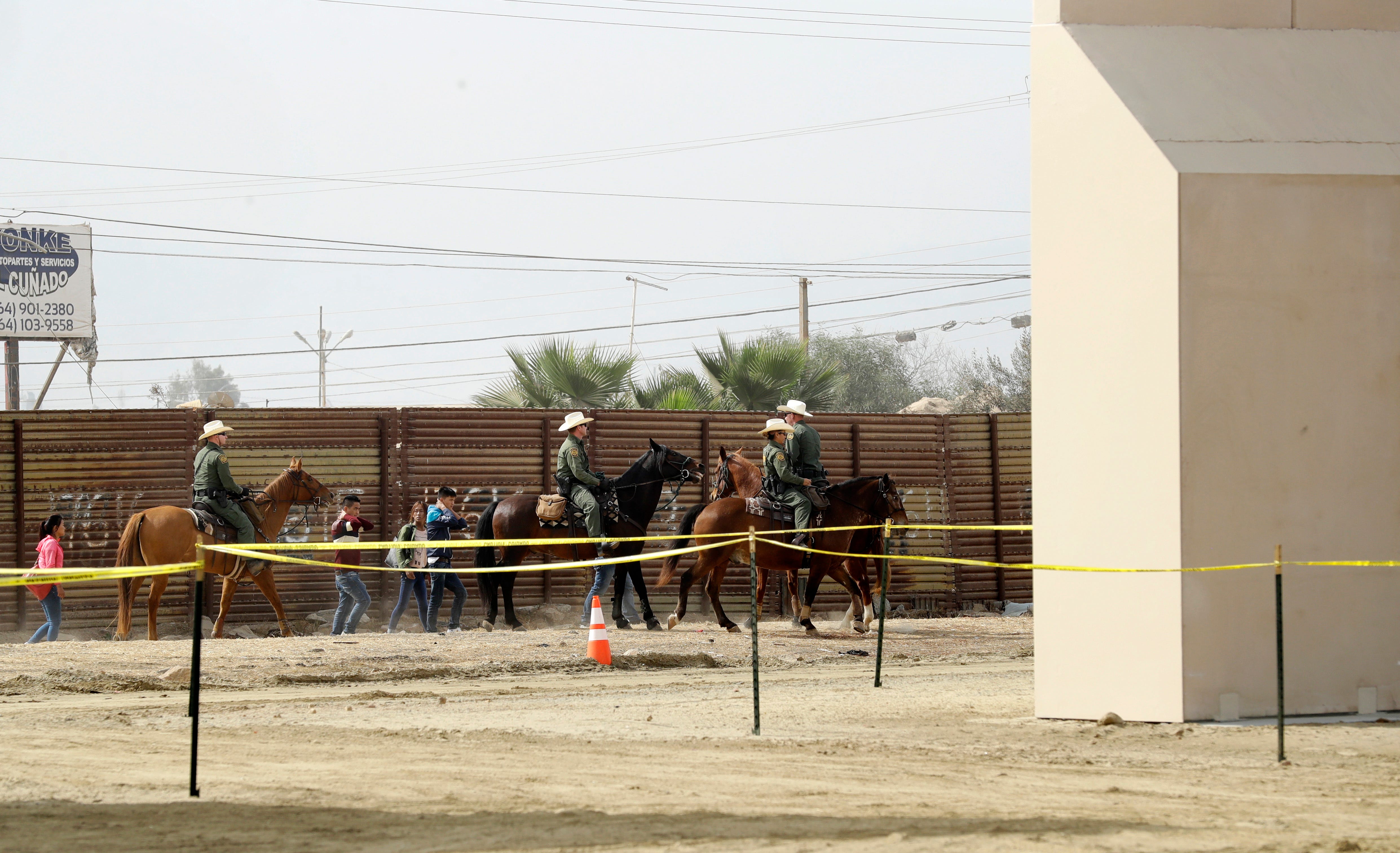 In this Oct. 19, 2017, file photo, a group of people are detained by Border Patrol agents on horseback after crossing the border illegally from Tijuana, Mexico, near where prototypes for a border wall, right, were being constructed in San Diego. More than 1,600 people arrested at the U.S.-Mexico border, including parents who have been separated from their children, are being transferred to federal prisons, U.S. immigration authorities confirmed Thursday, June 7, 2018. They said they’re running out of room at their own facilities amid President Donald Trump’s crackdown on illegal immigration. The move drew condemnation from activists who said the detainees may have legitimate claims to asylum and don’t deserve to be held in federal prisons. (AP Photo/Gregory Bull, File)