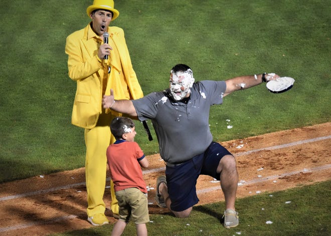 Savannah Bananas owner Jesse Cole, in a yellow tuxedo, narrates the action as a child delivers a pie to the face during the Bananas Premier Team's game against the Party Animals on March 27, 2021 at Hank Aaron Stadium in Mobile, Alabama. It was part of the