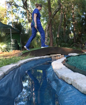 Stacy Craig walks across "Rae's Creek" on the "Hogan Bridge," part of her and husband Tommy's tribute to Augusta National's 12th green at their home in Ormond Beach.