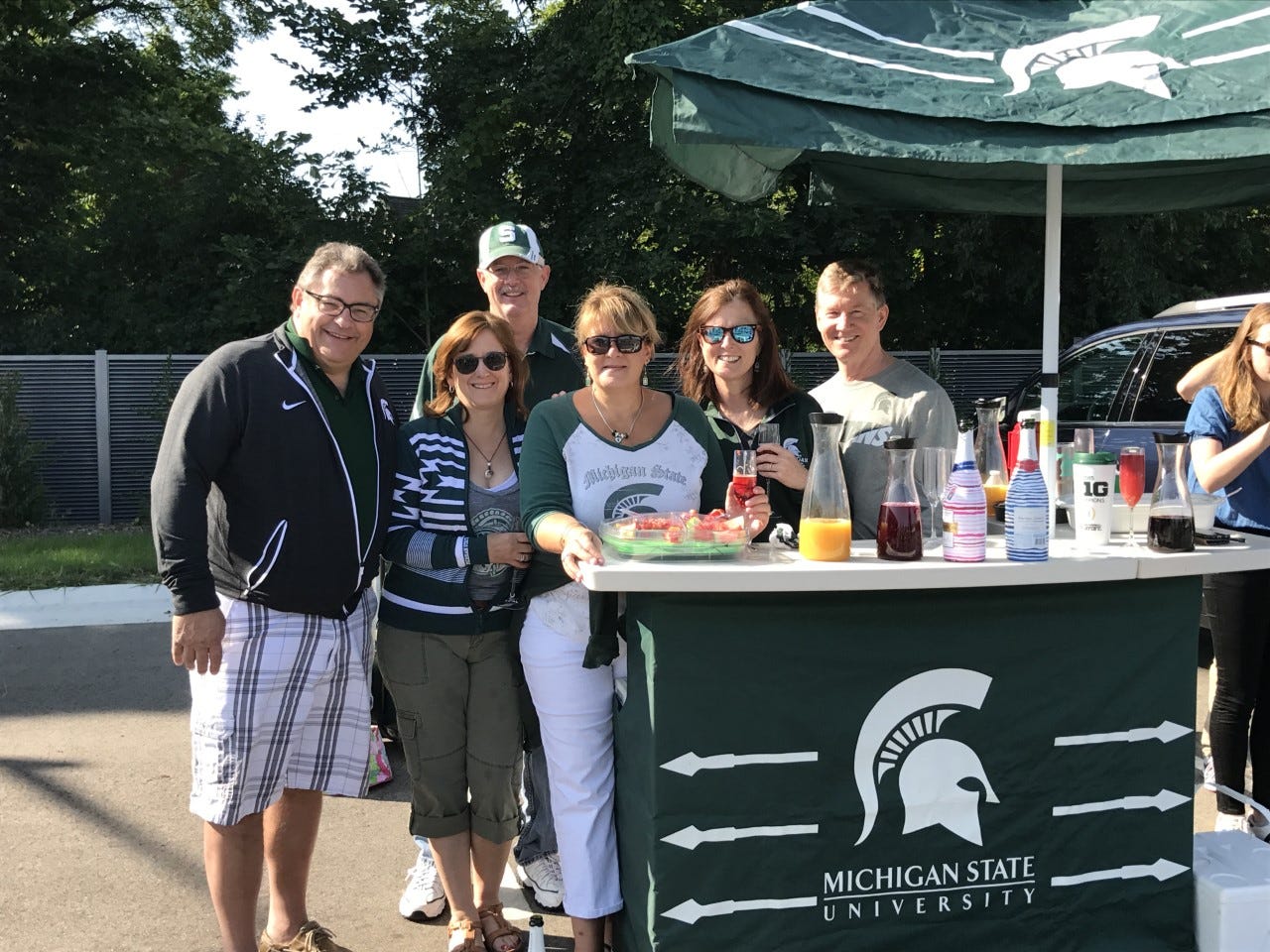 Michigan State football fan Laura Varon Brown, second from left, tailgates outside of Spartan Stadium before the COVID-19 pandemic with family and friends while using a popular portable Spartans bar.