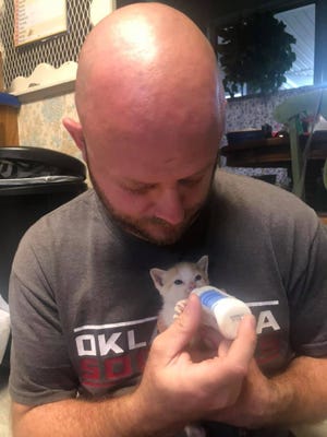 One of Oklahoma City Animal Welfare pet foster parents bottle feeds a kitten.