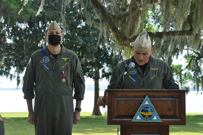 Capt. Jeffrey Hill (right), the incoming commanding officer of Naval Air Station Jacksonville, reads his orders at a change of command ceremony Friday. The outgoing commander, Capt. Brian Weiss, is at left.