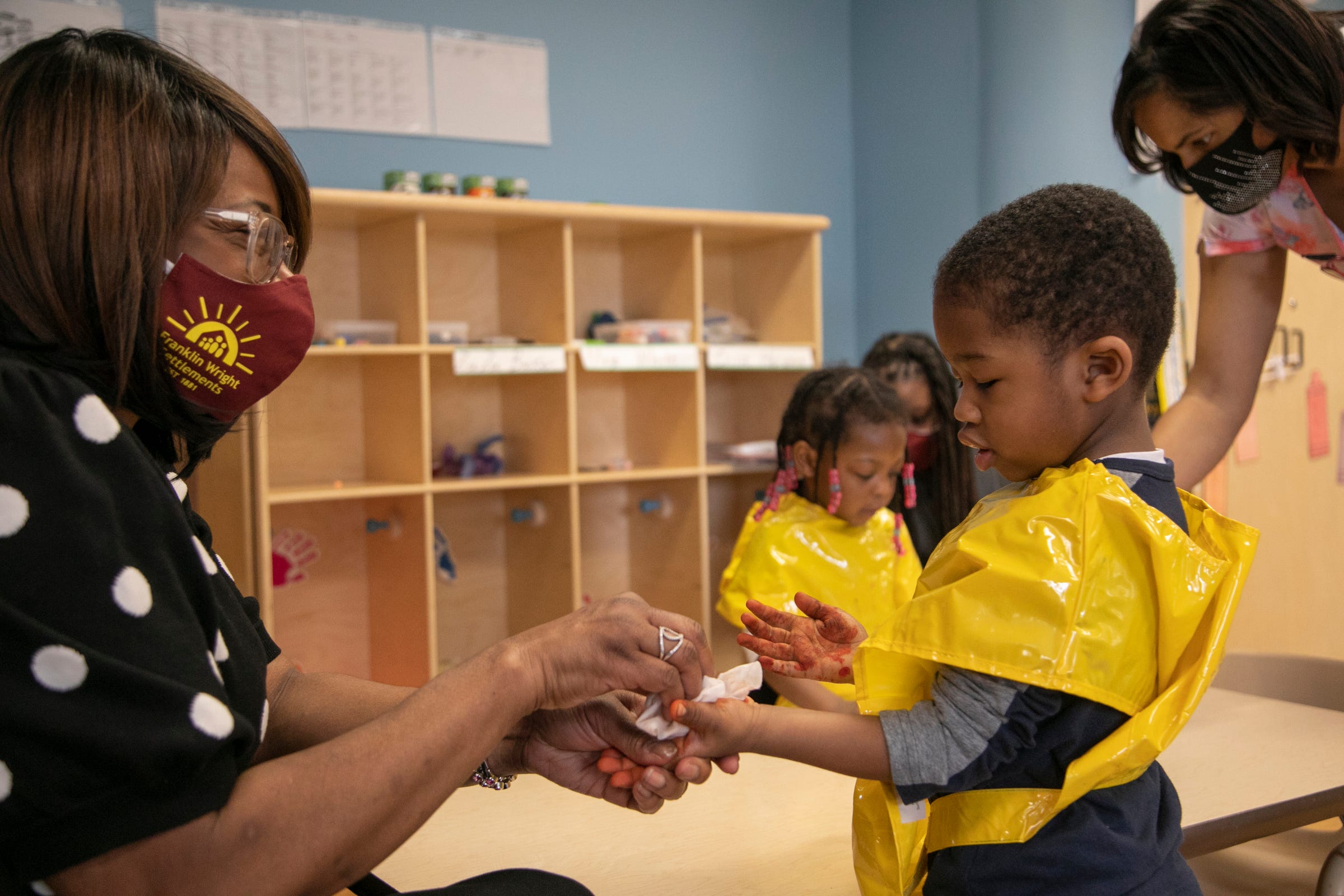 Monique Marks, President and CEO of Franklin Wright Settlements, left, helps clean the hands of Zion Taylor, 2, in his classroom on Mar. 11, 2021. The center turns 140 this year. The organization is all about helping Detroiters with basic life, social and family needs.