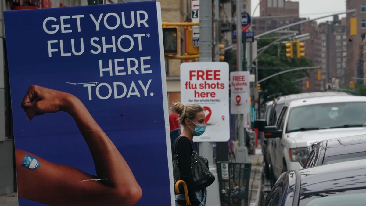 A woman walks past free flu shot advertisements outside of drugstores on August 19, 2020 in New York.