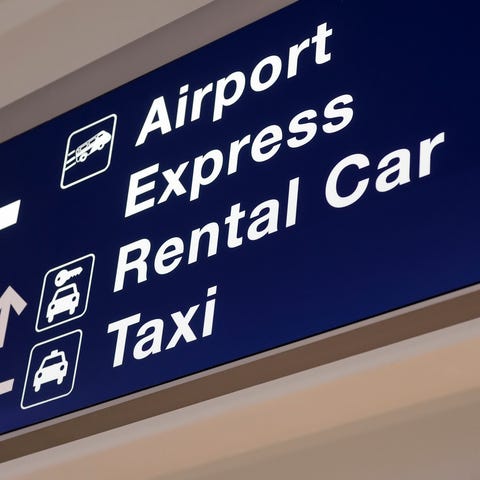 An airport sign with direction arrows for rental c