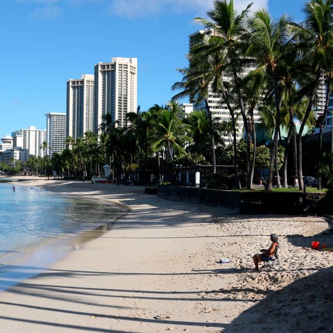 A man sits on a nearly empty Waikiki Beach in Hono