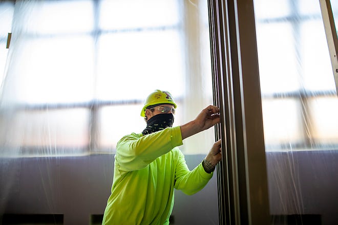 A worker assembles a frame in a second-floor hallway at Galesburg High School on Tuesday, April 13, 2021.