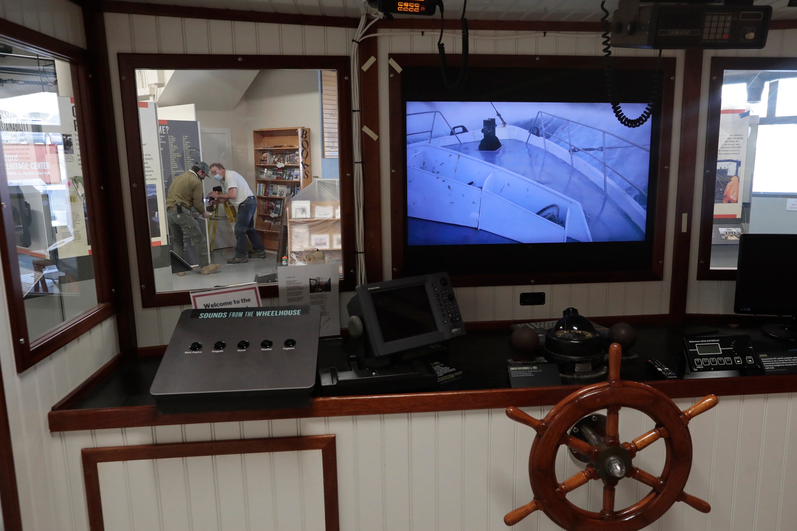 Matt Walsh and Stephen Walsh of WB Inc. carpenters, are seen through one of the windows on the bridge found inside of the New Bedford Fishing Heritage Center on Bethel Street in New Bedford, which is undergoing major renovations including More than a Job: Work and Community in New Bedford's Commercial Fishing Industry. The new exhibits are scheduled to open soon.