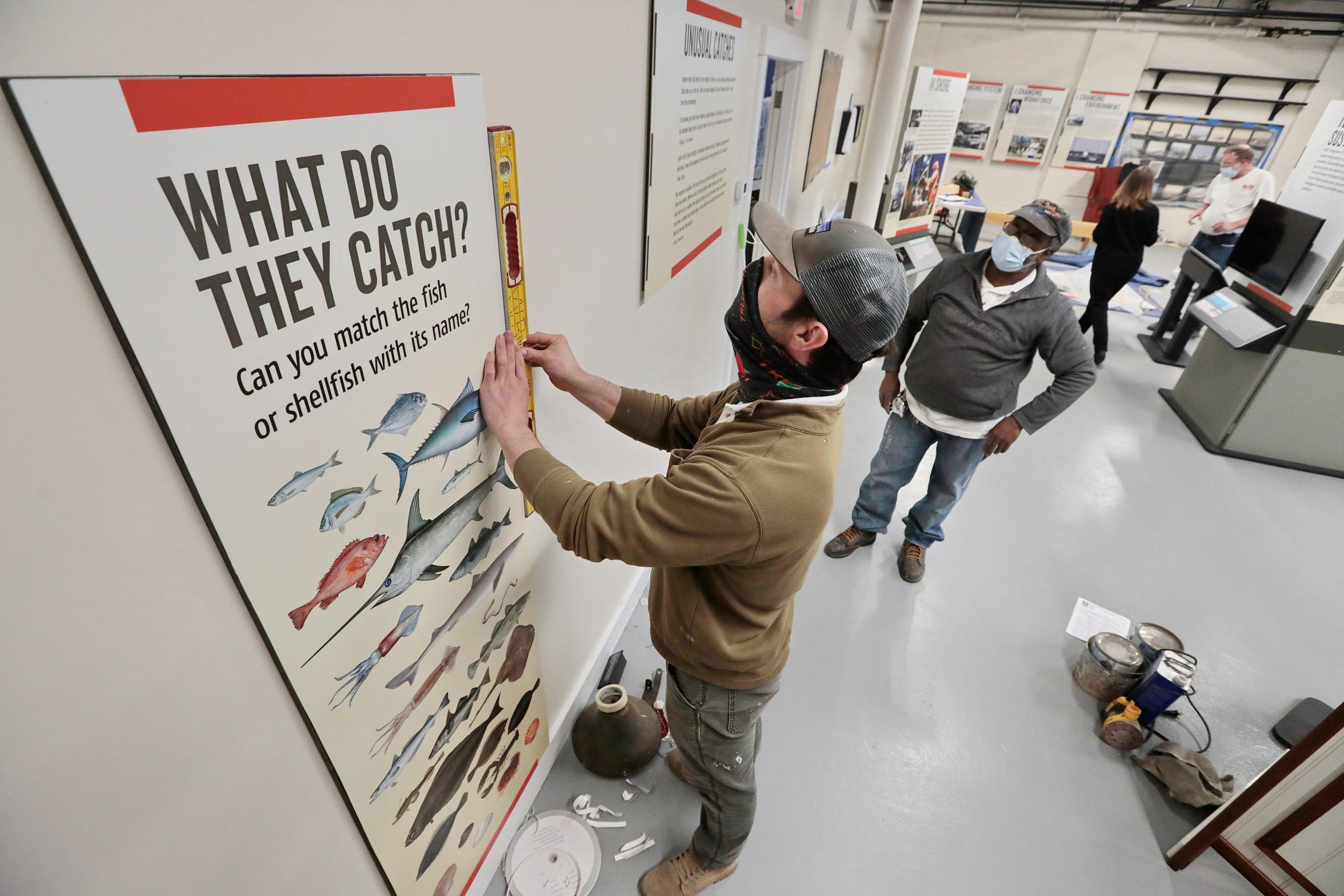 Matt Walsh and Mauro Moreira, of WB Inc. install an informational panel outlining the type of fish New Bedford fishermen catch. This one of the many new exhibits being installed inside of the New Bedford Fishing Heritage Center on Bethel Street in New Bedford, which is undergoing major renovations including More than a Job: Work and Community in New Bedford's Commercial Fishing Industry. The new exhibits are scheduled to open soon.