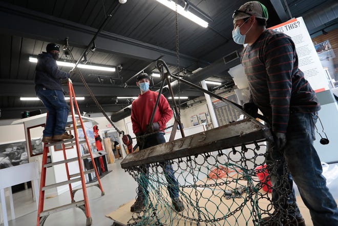 Sal Sequeira, Dave St. Pierre and Domingo Ixcuna Lucas of Blue Fleet Welding Services, install a one-third scale scallop dredge they manufactured, inside of the New Bedford Fishing Heritage Center.  This is one of the many new exhibits soon to open.