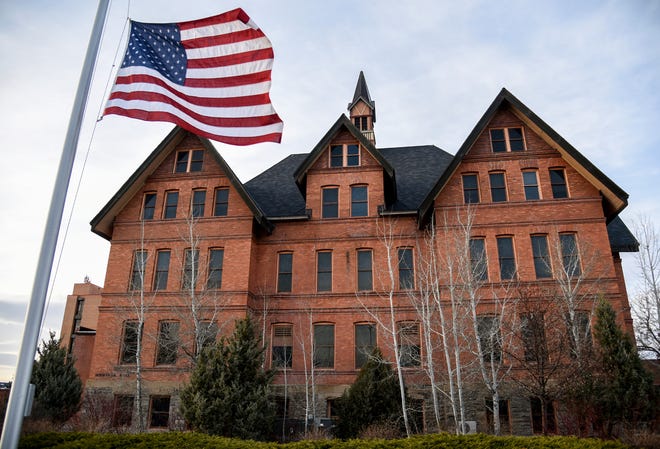 In this April 2, 2021, photo, an American flag flies at half-staff in front of Montana Hall at Montana State University in Bozeman, Mont. The flag was at half-staff in honor of the victims of an attack at the U.S. Capitol that day. The Montana University System is looking at neighboring states and seeking public input as it prepares to allow concealed firearms on campuses beginning on June 1, as required under a bill signed by Republican Gov. Greg Gianforte. (Rachel Leathe/Bozeman Daily Chronicle via AP)