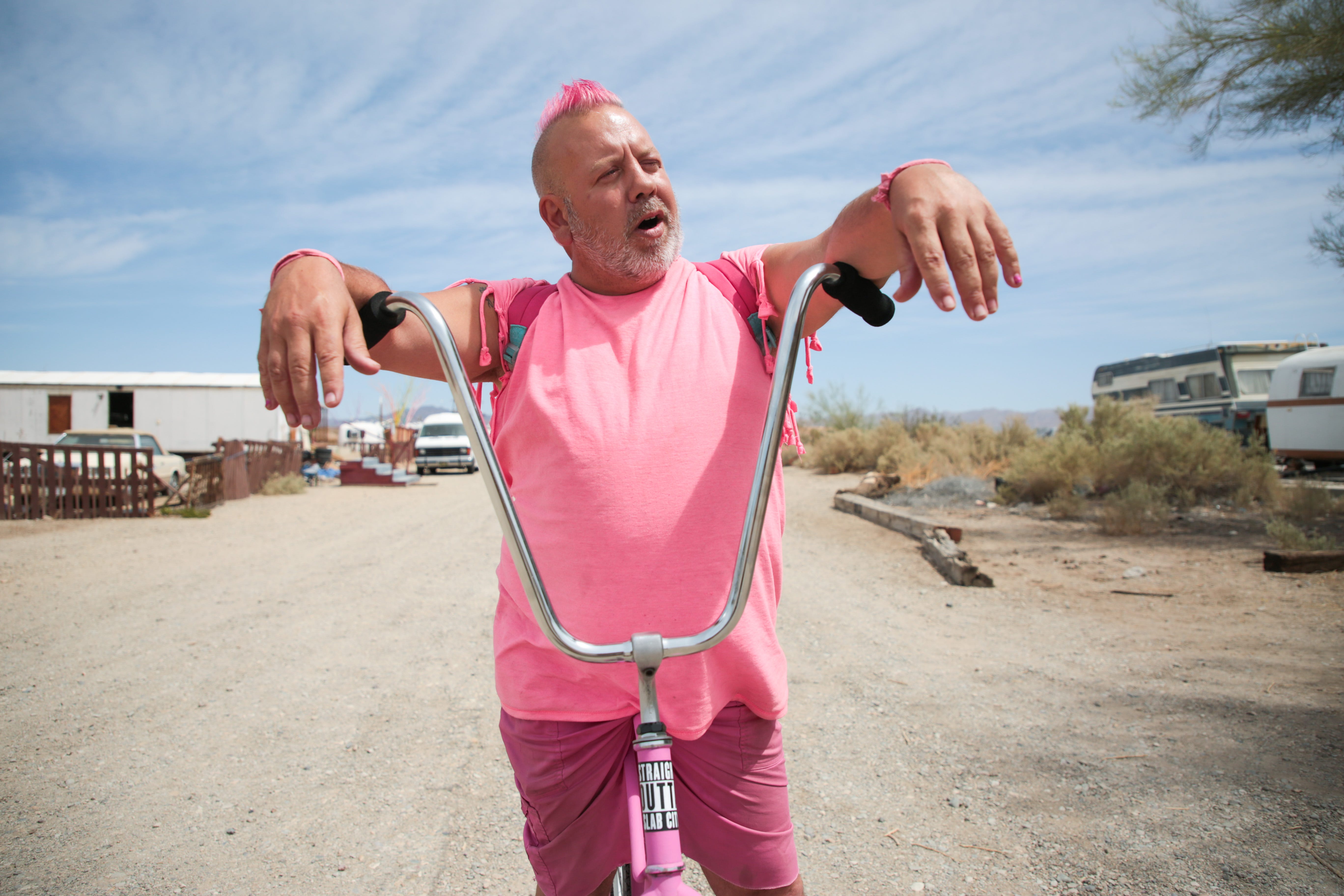 Pink Gorilla stops to chat on his bike in Slab City, Calif., on Monday, April 5, 2021. He said he believes the COVID-19 pandemic is a hoax and will not get the vaccine.