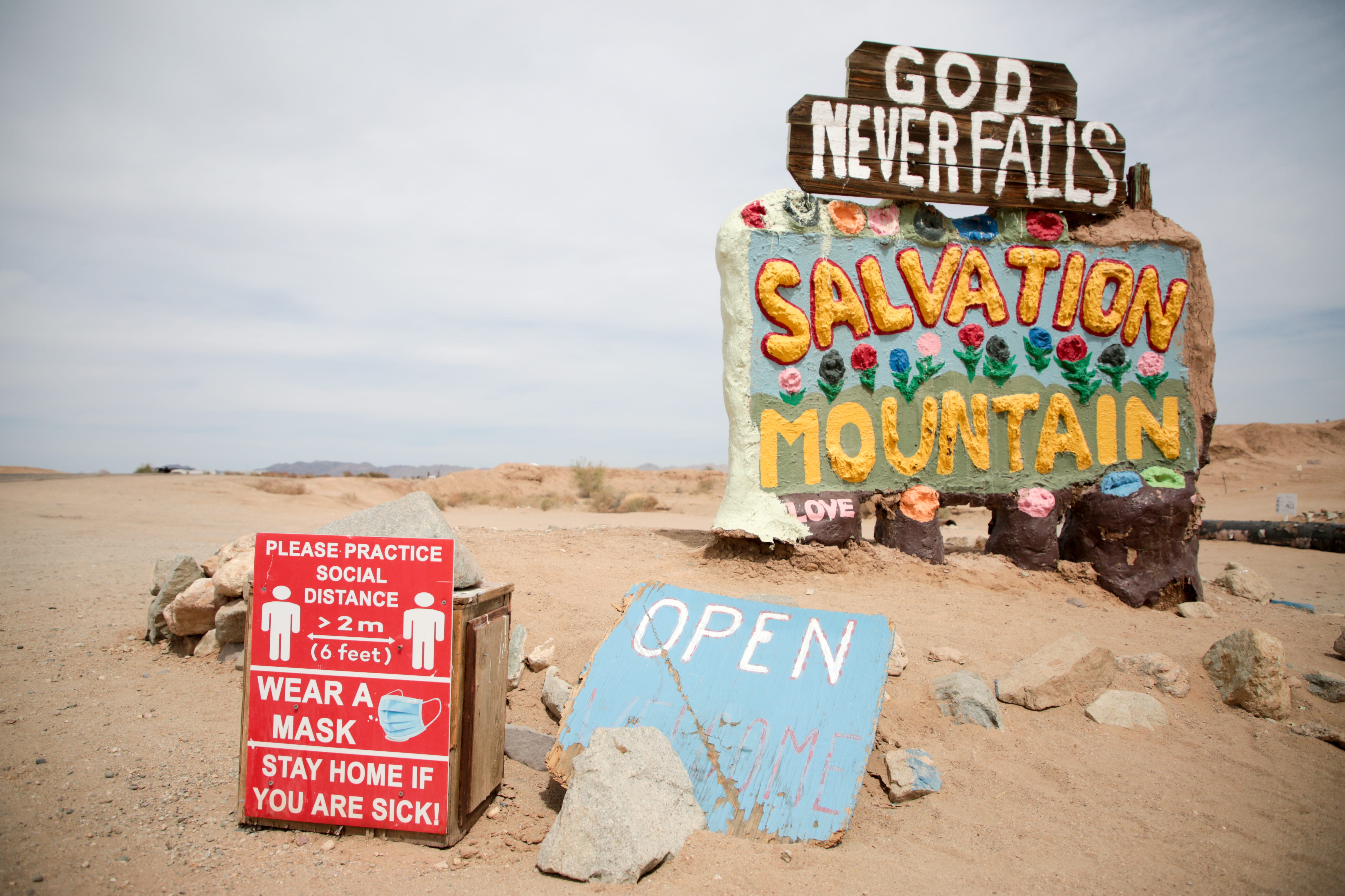 A sign encouraging social distancing and mask wearing rests near Salvation Mountain, just outside Slab City, Calif., on Monday, April 5, 2021.