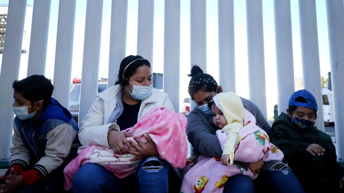 TIJUANA, MEXICO - FEBRUARY 19:  El Salvador and Honduras nationals seeking asylum in the United States sit outside the El Chaparral border crossing on February 19, 2021 in Tijuana, Mexico. Those seeking asylum have been waiting months and years in Tijuana and other locations to be allowed into the U.S. to petition for asylum. Starting today, a small group out of an estimated 25,000 asylum seekers with active cases will be allowed into the U.S., a Biden   administration move reversing a Trump administration immigration policy that was informally referred to as "Remain in Mexico."  (Photo by Mario Tama/Getty Images)