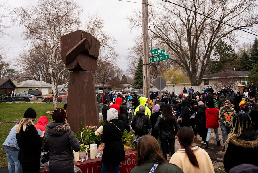 People gather around a sculpture of a raised fist during a vigil for Daunte Wright on April 12, 2021 in Brooklyn Center, Minnesota. Wright was shot and killed yesterday by Brooklyn Center police during a traffic stop. The fist sculpture first appeared over the summer at the memorial for George Floyd, the artist Jordan Powell-Karis brought it to the site where Wright was killed today.