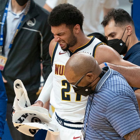 Jamal Murray is helped off the floor after injurin