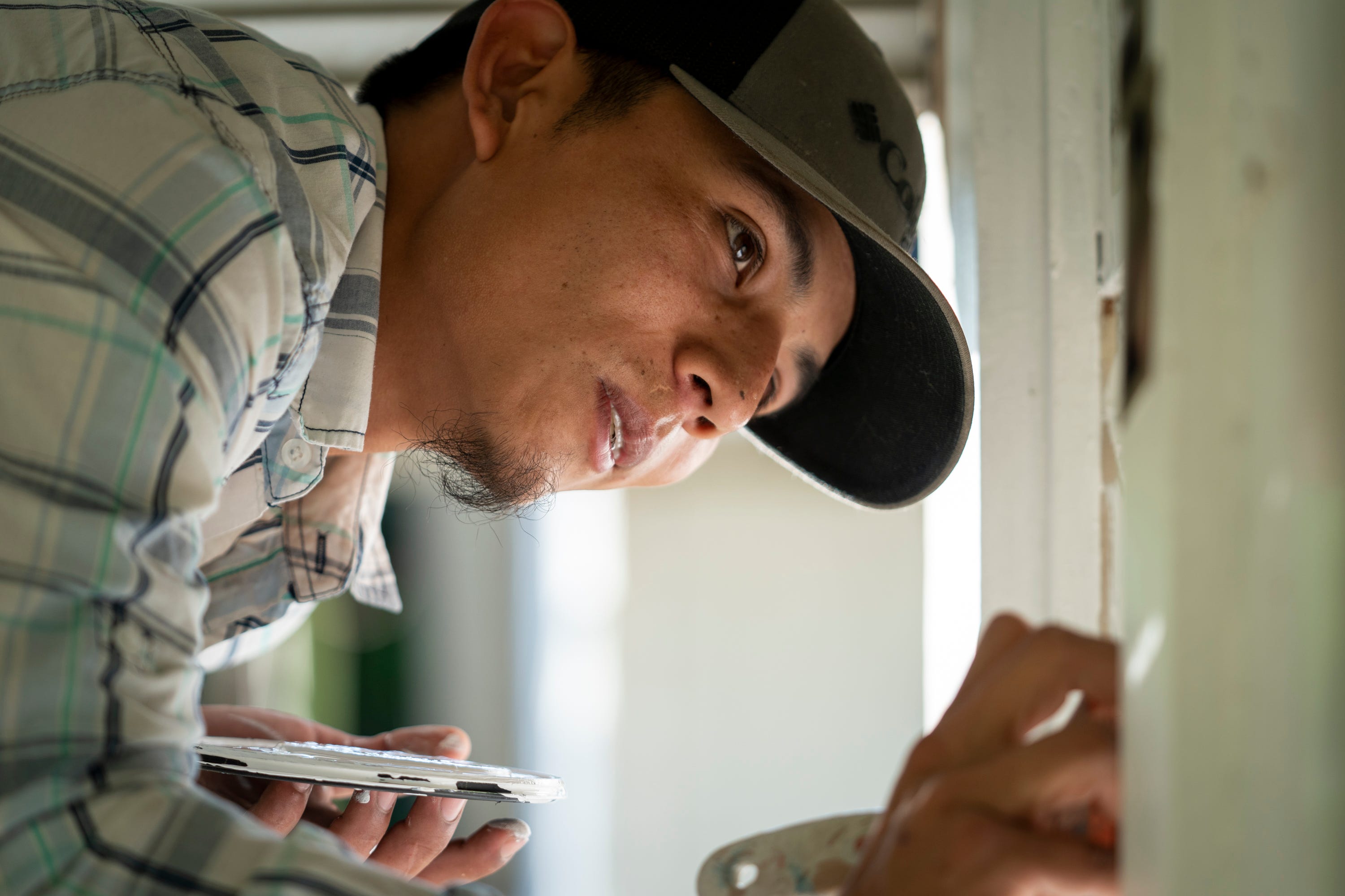 Francis Portillo paints windows at a home before an inspection in Jacksonville, Fla., on April 8.