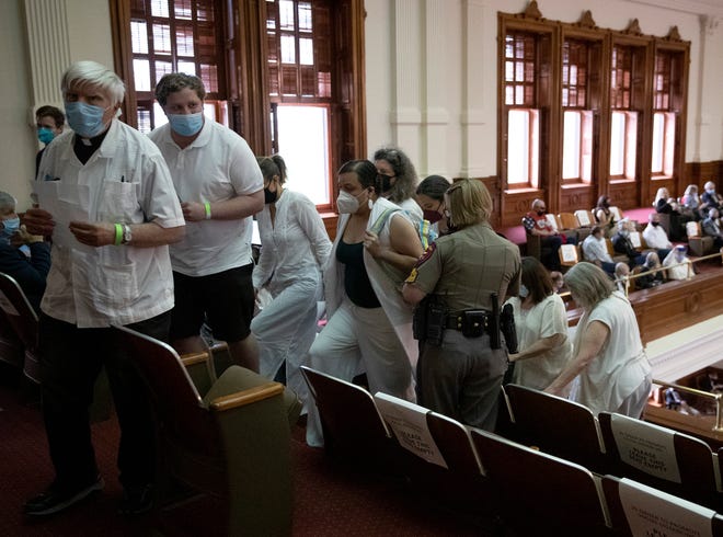 A group of gun-control advocates, including Rev. Bruce Nieli, left, are escorted out of the Texas House chamber by a state trooper Thursday after they began praying and singing while lawmakers were debating House Bill 1927, which would let people carry handguns without permits.