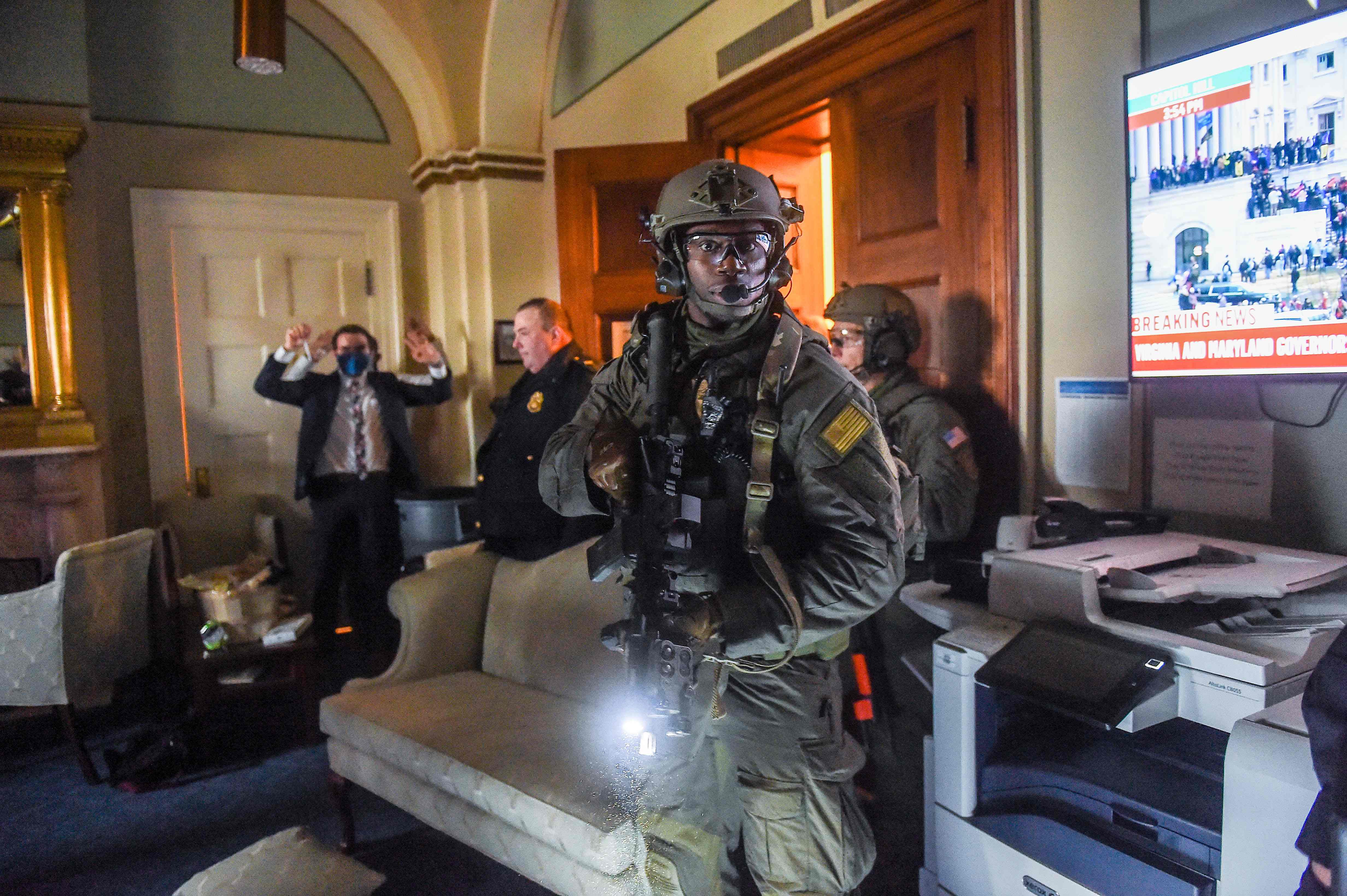 A congressional staffer holds his hands up while the Capitol Police Swat team checks everyone in the room as they secure the floor from supporters of then-President Donald Trump in Washington, D.C., on Jan. 6, 2021.