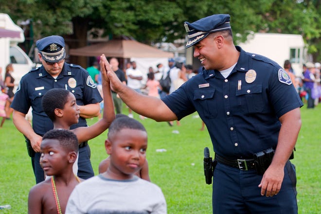 Camden County Police Chief Gabriel Rodriguez, right, high fives a member of the community. Rodriguez, a native of Camden, which is heavily Black and Latino, said crime in his city is declining in part due to repeated training sessions that encourage officers to use restraint whenever possible when interacting with citizens.