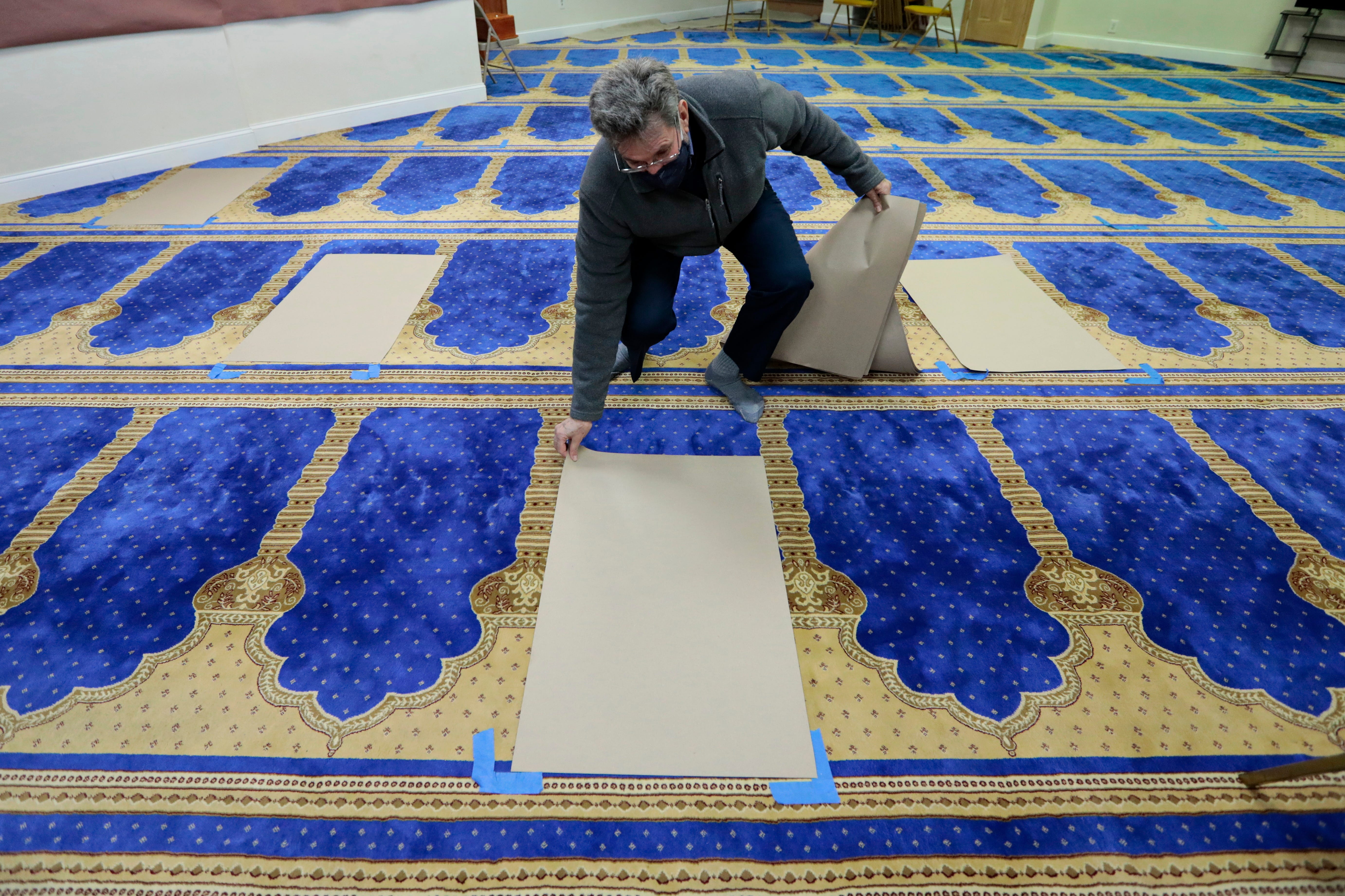 Martin Bentz, outreach coordinator of the Islamic Society of Southeastern Massachusetts, places the socially distanced markers where worshippers will stand during their daily Ramadan prayers.