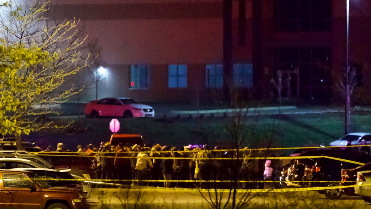 People stand outside a FedEx facility near Indianapolis International Airport after a shooting with multiple victims was reported late Thursday night, April 15, 2021.