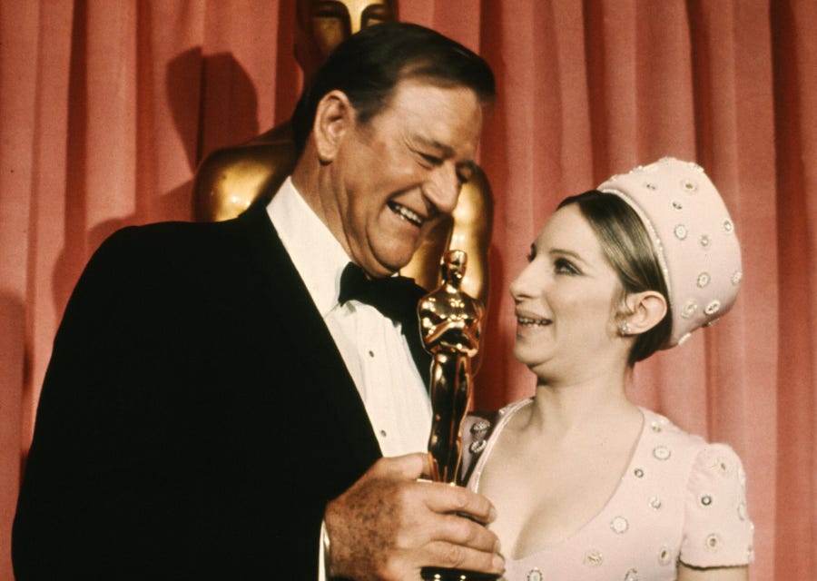 John Wayne accepts his Best Actor Oscar from US singer and actress Barbra Streisand in 1969.