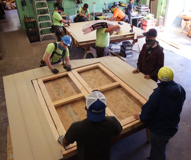 Volunteers, carpentry students and teachers assemble walls of sheds at the McKenzie High School wood shop in Blue River on Saturday. The sheds will be assembled on sites around the valley later for people who lost their homes and businesses to the Holiday Farm Fire.