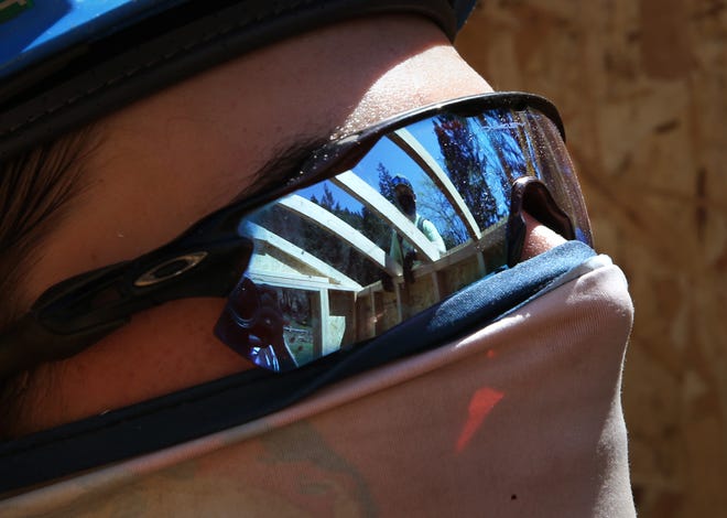 Rafters reflect in the sunglasses of Chambers Construction apprentice Gunnar Larsen as he helps construct a shed for people who lost their homes to the Holiday Farm Fire on Saturday.