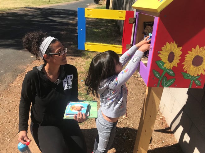 A child reaches for a book at a recently installed Little Free Library placed at Mariposa Park in Phoenix.