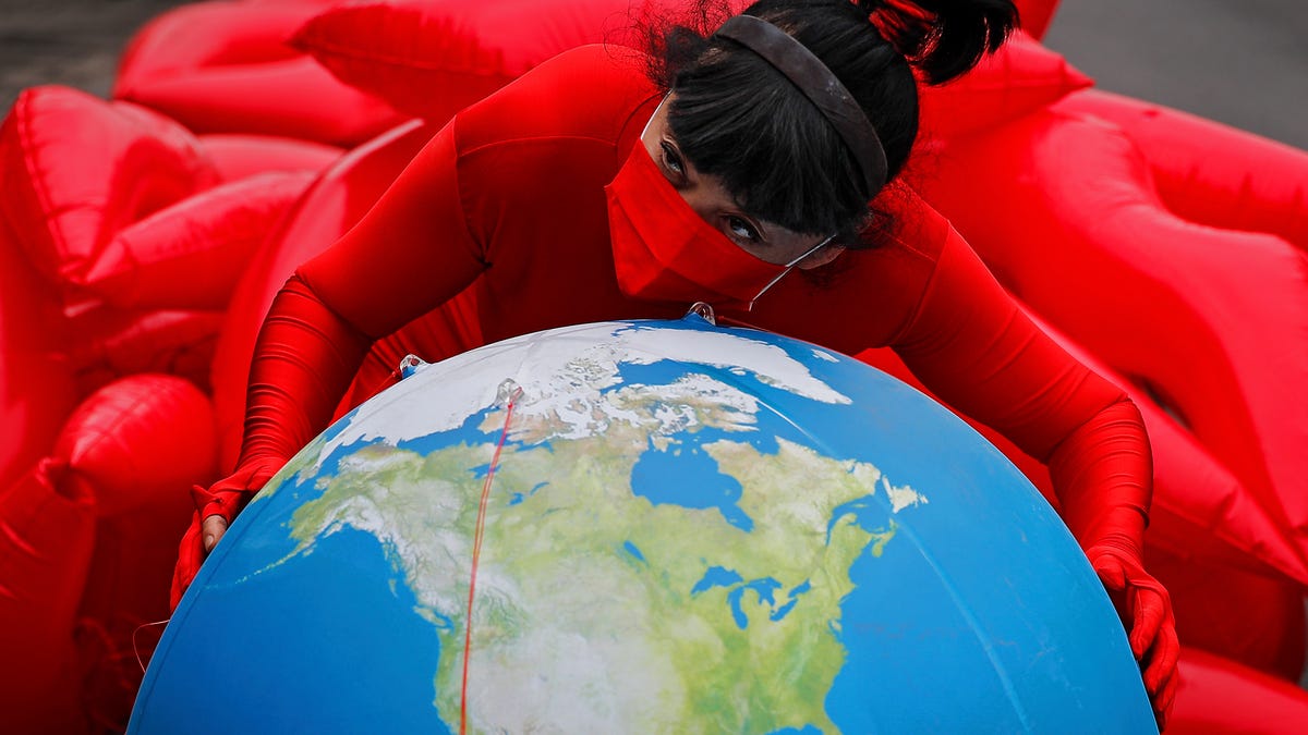 Artist and environmental activist Kong Ning wearing her latest gown collection with a theme "Kiss the earth" posing on a globe in support on Earth Day in Beijing, Thursday, April 22, 2021.